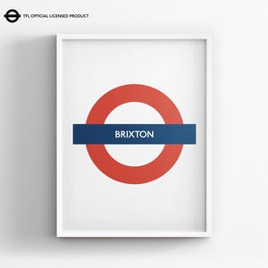 May include: A framed wall art print featuring the iconic London Underground roundel logo with a red circle and a blue horizontal bar containing the white text BRIXTON. The top left corner includes the text TFL OFFICIAL LICENSED PRODUCT.