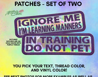 May include: A set of two rectangular 6 inch by 2 inch patches with purple borders and purple embroidered text on a holographic silver background. The top patch reads IGNORE ME I'M LEARNING MANNERS and the bottom patch reads IN TRAINING DO NOT PET.