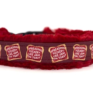 May include: Burgundy dog collar with a plush red lining. The collar features a repeating pattern of toast with the text "SPREADING FUCKERY LIKE JAM ON TOAST" in a playful font. A fun accessory for pets.
