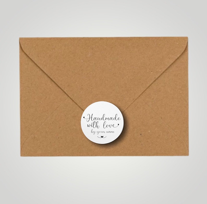 Może przedstawiać: Okrągła biała naklejka z czarnym tekstem, kt&oacute;ry brzmi "Handmade with love by your name" z małym symbolem serca.