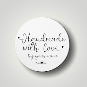 Może przedstawiać: Biała okrągła naklejka z czarnym tekstem, kt&oacute;ry brzmi "Handmade with love by your name" z małym symbolem serca nad tekstem i małym symbolem serca pod tekstem.