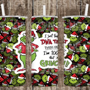 May include: A green and red tumbler with a Grinch design. The tumbler has a white lid and a straw. The text on the tumbler reads "I just took a DNA test, turns out I'm 100% that Grinch!"
