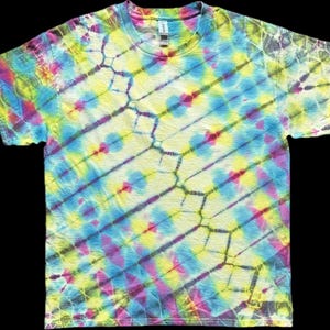 Puede incluir: Camiseta de manga corta y cuello redondo con estampado tie-dye. El diseño presenta rayas diagonales en tonos amarillos, azules, rosas y morados, creando un efecto colorido y llamativo. La camiseta está hecha de un material suave.