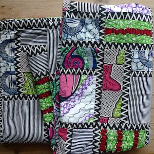 May include: Two colorful patchwork quilts with a variety of patterns. The quilts feature squares of fabric with bold prints in pink, green, blue, and white. The edges are trimmed with black and white zigzag and striped patterns.