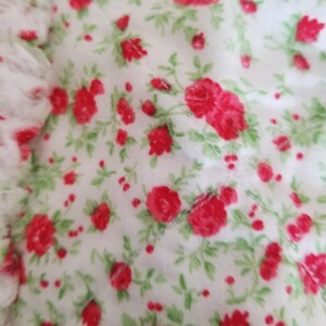 Pu&ograve; includere: Tessuto bianco con un motivo ripetuto di piccole rose rosse e foglie verdi.