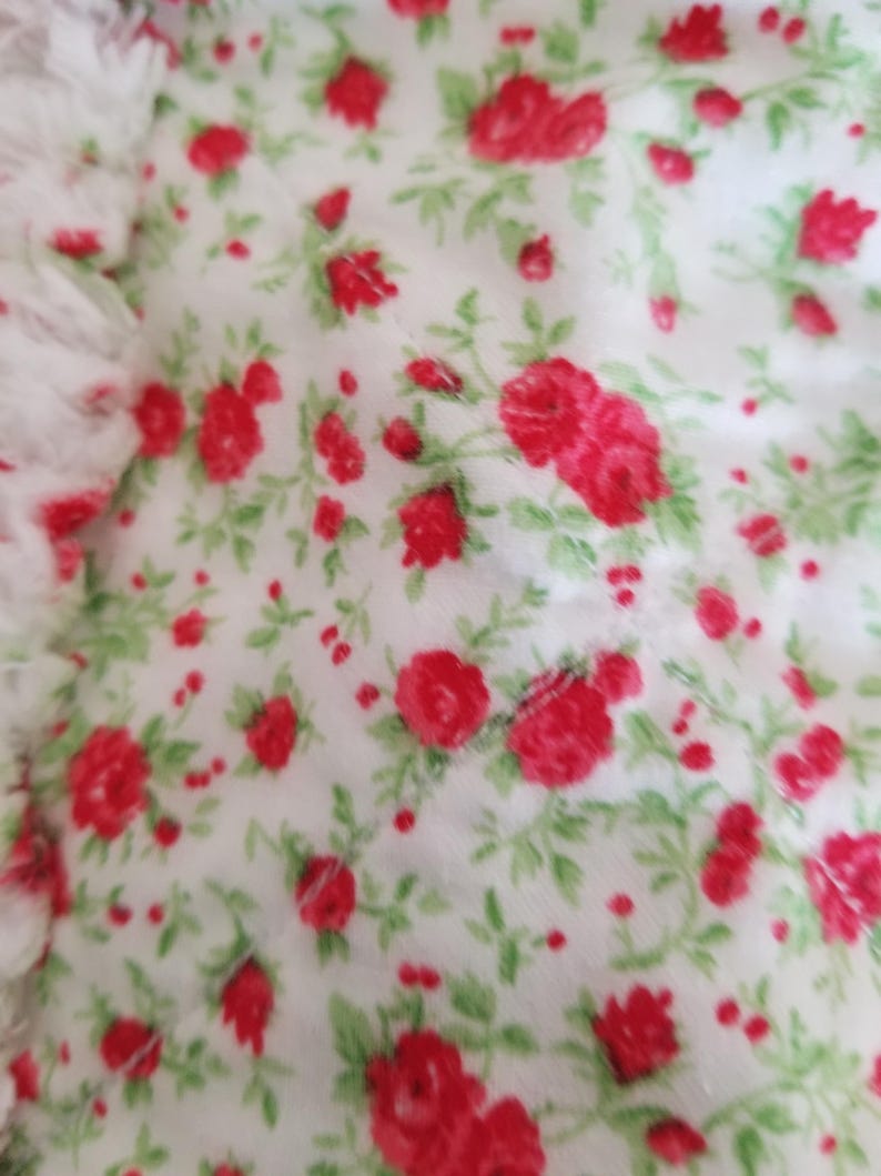Pu&ograve; includere: Tessuto bianco con un motivo ripetuto di piccole rose rosse e foglie verdi.