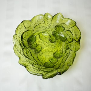 Pode incluir: Uma tigela de vidro verde com um design de folhas e acentos de bagas em relevo. A tigela é perfeita para servir frutas ou lanches.