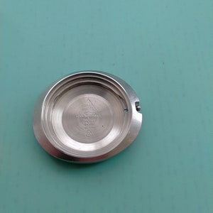 May include: A silver watch case back with the text "AUTOMATIC CHRONOMETER" and "SWISS MADE" printed on it.