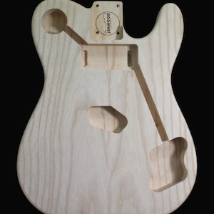 May include: Unfinished natural wood guitar body with cutouts for pickups, controls, and a bridge. The body is made of alder wood and has a natural finish. The body is labeled "JBRWOOD" in the upper right corner.