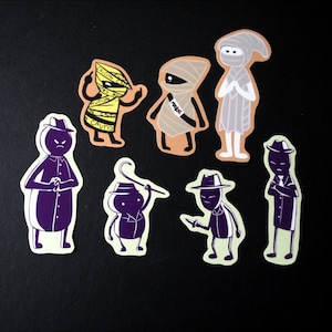 Puede incluir: Conjunto de ocho pegatinas con diferentes personajes. Los personajes están dibujados en un estilo simple y de dibujos animados, y son principalmente en blanco y negro. Algunos personajes llevan sombreros, y un personaje lleva un atuendo a rayas amarillo y negro. Las pegatinas están impresas en papel blanco.