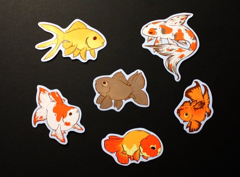 May include: Six goldfish stickers in various colours. The stickers depict different goldfish breeds in shades of gold, orange, brown, and white, with detailed fin and body designs. The stickers are set against a black background.