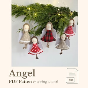 May include: Handmade angel ornaments with fabric dresses in various patterns, including polka dots and plaid. Each angel has yarn hair, fabric wings, and is suspended from a green garland. The word "Angel" is displayed below the ornaments.
