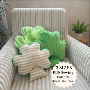Puede incluir: Tres cojines con forma de trébol en tonos verdes y beige, con estampados a rayas y texturizados. Están colocados sobre un sillón de pana color crema. El texto en la imagen dice: "3 TAMAÑOS PDF Sewing Pattern Descarga Digital."