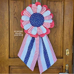 May include: A patriotic door decoration resembling a large rosette, featuring red, white, and blue fabrics. The central circle is blue with white stars, surrounded by red and white striped and dotted petals. The text reads "DIY PATTERN 80cm BIG DOOR DECOR".