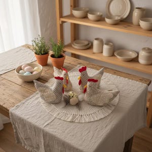 Four handmade fabric chickens arranged around speckled Easter eggs on round woven placemat in rustic spring kitchen interior.