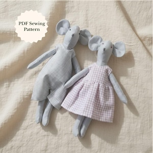 May include: Two handmade stuffed mouse dolls. One mouse wears a gray and white gingham dress, the other wears a pink and white gingham dress. Both have gray bodies, ears, arms, and legs. The text "PDF Sewing Pattern" is in a cream-colored circle.