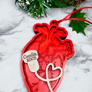 May include: Red wooden heart ornament with a stethoscope and a small tag that says "Cecelia, RDCS".