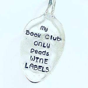 May include: A silver spoon with the text "my book club only reads wine labels" engraved on it.