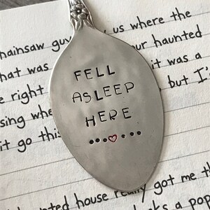 May include: A silver spoon with the words "FELL ASLEEP HERE" engraved on it. The spoon has a small red heart in the middle of the text.