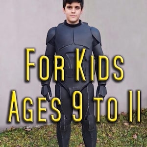May include: A dark gray, full-body armored costume featuring segmented chest, shoulder, arm, and leg plating with visible seam lines. The text FOR KIDS AGES 9 TO 11 is overlaid in yellow. The suit includes matching gloves and footwear.