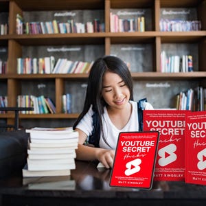 May include: Three red books titled "YouTube Secret Hacks" with a white play button icon. The books are stacked on a table in front of a young woman.