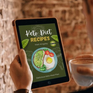 May include: A digital tablet displaying a book cover for "Keto Diet Recipes" by Matt Kingsley. The cover features a green background with a drawing of a plate of avocado toast and a fried egg. The text "Keto Diet" is in a white cursive font and the text "Recipes" is in a white sans-serif font.