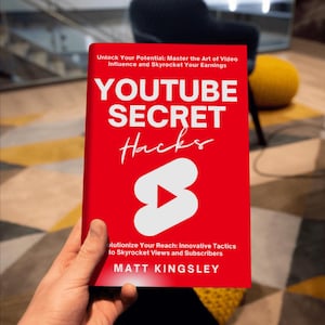 May include: A red book titled "YouTube Secret Hacks" with a white play button icon. The book cover also includes the text "Unlock Your Potential: Master the Art of Video Influence and Skyrocket Your Earnings" and "Revolutionize Your Reach: Innovative Tactics to Skyrocket Views and Subscribers". The author's name is "Matt Kingsley".