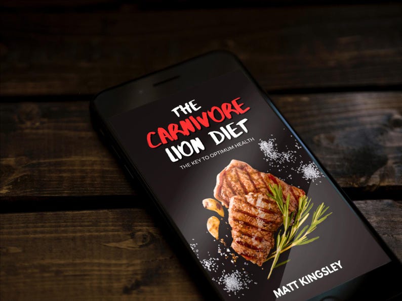 Puede incluir: Un tel&eacute;fono inteligente que muestra la portada de un libro con el t&iacute;tulo "The Carnivore Lion Diet: The Key to Optimum Health" en texto rojo y blanco. La portada presenta un primer plano de carne a la parrilla con romero y ajo sobre un fondo negro.