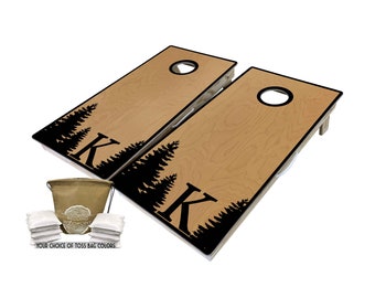 May include: Two wooden cornhole boards with a black forest silhouette design and the letter "K". Includes a set of white toss bags and a carrying bag. The boards have a hole in the top for tossing bean bags.