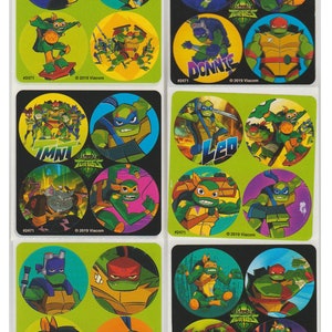 May include: A sheet of stickers featuring the Teenage Mutant Ninja Turtles. The stickers are round and feature different characters from the show, including Leonardo, Donatello, Raphael, and Michelangelo. The stickers are on a green background with the words "Teenage Mutant Ninja Turtles" printed on them.