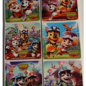 May include: Six colorful stickers featuring the characters from the cartoon show Paw Patrol. The stickers feature the characters in a jungle setting with dinosaurs. The text on the stickers reads "PAW Patrol Dino Rescue".