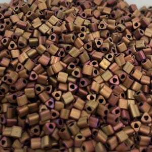 May include: A large pile of small, triangular-shaped beads in a metallic bronze color with a slight iridescent purple sheen.