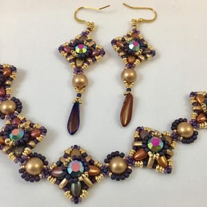 Könnte beinhalten: Ein Set aus goldenen und violetten Perlen-Schmuck mit geometrischem Design. Das Set beinhaltet ein Armband und ein Paar Ohrringe.