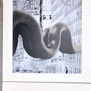 Könnte beinhalten: Ein Schwarzweißfoto einer großen, abstrakten Skulptur in Form einer verdrehten, fließenden Form. Die Skulptur ist vor dem Hintergrund einer Stadtkulisse mit hohen Gebäuden platziert.