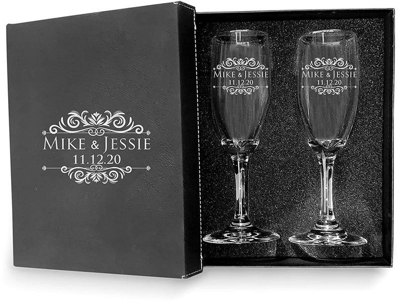May include: Two engraved champagne flutes in a black gift box. The flutes are etched with the names "Mike & Jessie" and the date "11.12.20".