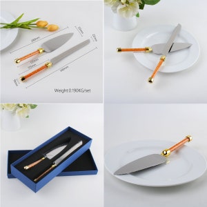 May include: A set of two cake servers with orange and gold handles. The servers are in a blue box and on a white plate. The servers are 13.5 inches long and 5.5 inches wide. The set weighs 0.190 kg.