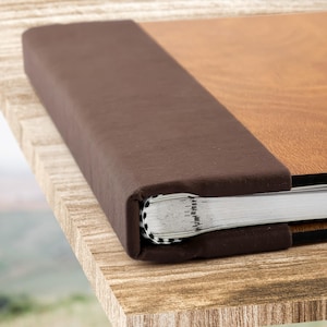 May include: A brown leather-bound photo album with a wood-grain cover. The album is closed and the spine is visible.