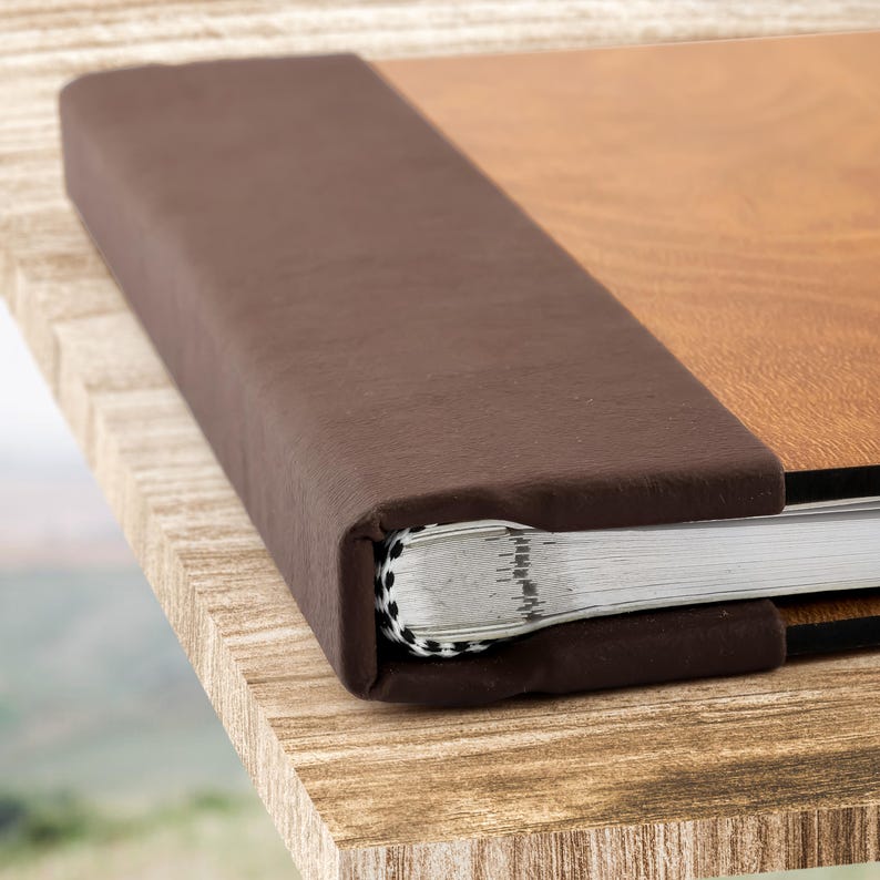 May include: A brown leather-bound photo album with a wood-grain cover. The album is closed and the spine is visible.