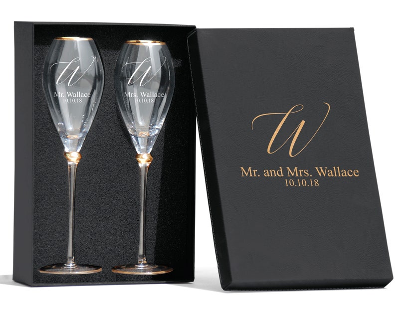 May include: Two champagne flutes with gold rims and engraved initials "W" and the names "Mr. Wallace 10.10.18" and "Mrs. Wallace 10.10.18". The flutes are in a black box with a gold "W" and the text "Mr. and Mrs. Wallace 10.10.18".