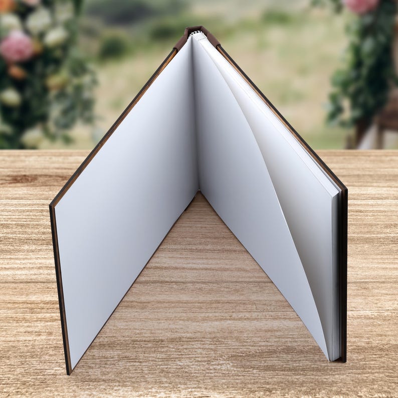 May include: A brown leather-bound journal with blank pages, open to reveal the white paper inside. The journal is lying flat on a wooden surface.