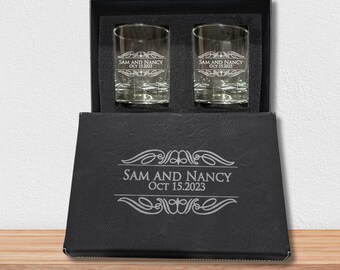 May include: A black gift box with two clear glass shot glasses engraved with the text "Sam and Nancy Oct 15, 2023".