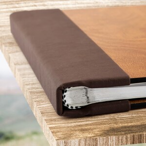 May include: A brown leather-bound photo album with a wood-grain cover. The album is closed and the spine is visible.