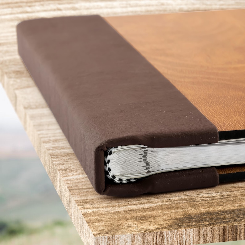May include: A brown leather-bound photo album with a wood-grain cover. The album is closed and the spine is visible.