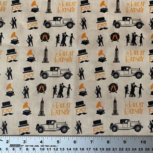 May include: A beige fabric with a repeating pattern of black silhouettes of people dancing, cars, and buildings. The text "The Great Gatsby" is repeated throughout the pattern in orange lettering.