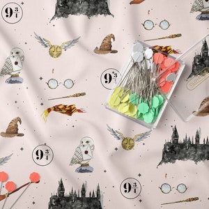 Könnte beinhalten: Ein rosa Stoff mit einem sich wiederholenden Muster aus Harry-Potter-Motiven. Die Illustrationen zeigen das Hogwarts-Schloss, einen goldenen Schnatz, einen Zaubererhut, eine Brille, einen Zauberstab, einen Schal, eine Eule und die Zahl "9 3/4".