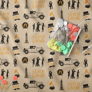 May include: A beige fabric with a repeating pattern of black silhouettes of people dancing, cars, buildings, and gramophones. The text "The Great Gatsby" is repeated throughout the pattern.
