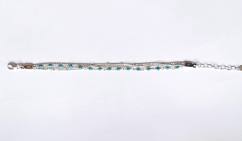 May include: A silver bracelet with multiple chains and turquoise beads.