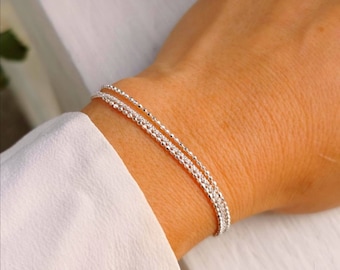 May include: A silver chain bracelet with three strands of different sized beads.