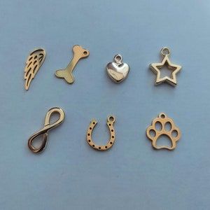 May include: Eight gold-colored metal charms in the shape of a wing, bone, heart, star, infinity symbol, horseshoe, paw print, and a star.