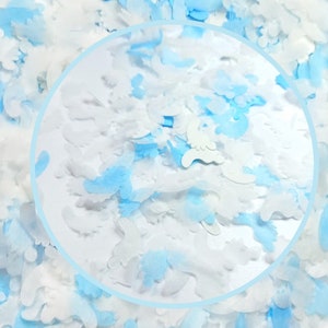 May include: A close-up of blue and white confetti, with a circular cutout revealing more confetti. The confetti is shaped like small, irregular shapes.